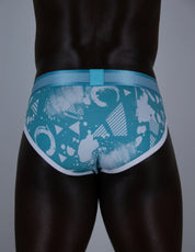 A close-up rear view of a model wearing teal and white patterned briefs with a matching waistband.