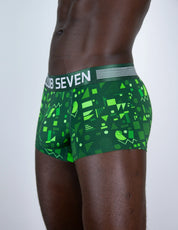 A close-up side view of a male model wearing green boxer briefs with a geometric pattern and a white waistband that reads 'CLUB SEVEN'.