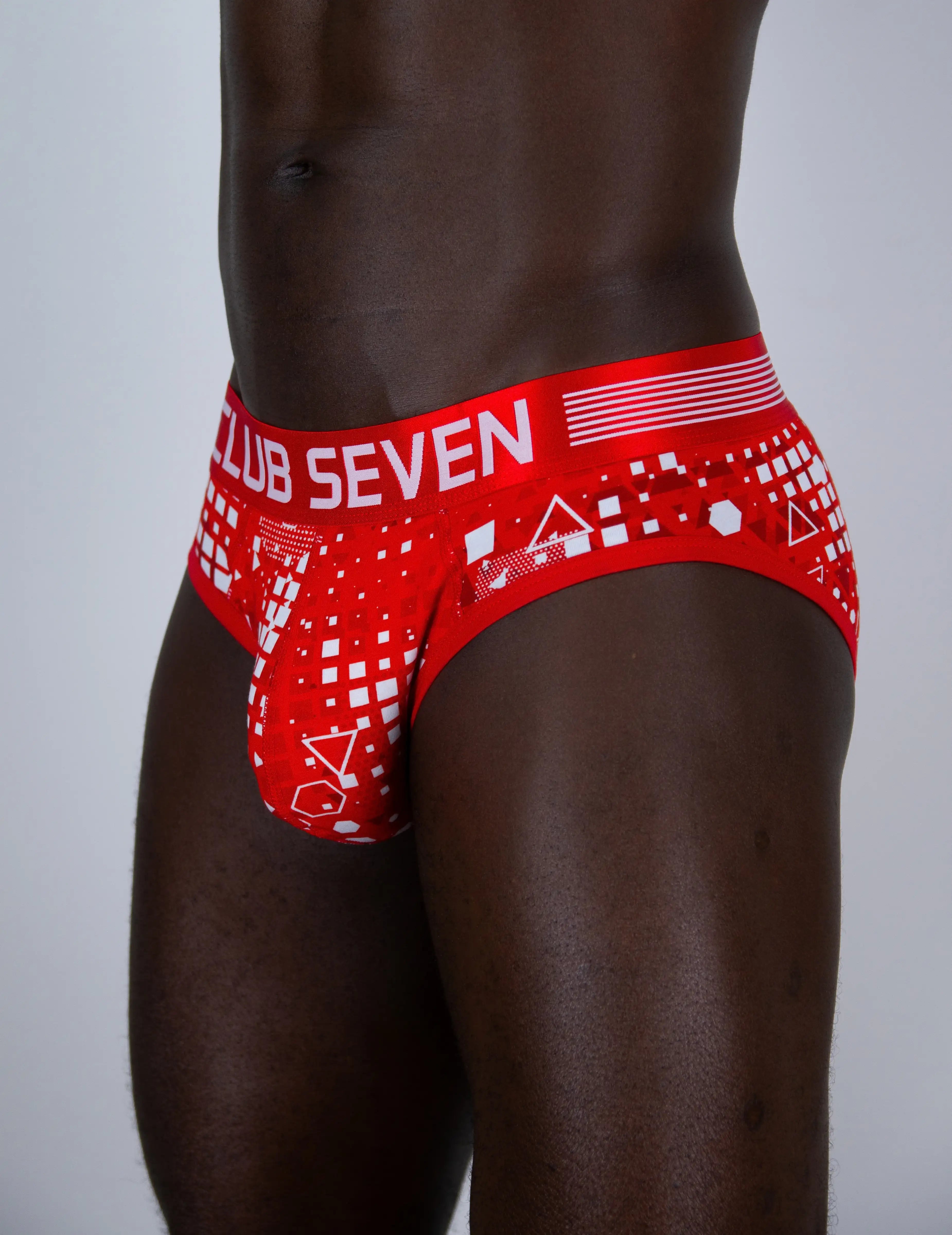 Red and white patterned men's briefs worn by a male model, featuring the text 'CLUB SEVEN' on the front waistband.