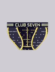 A pair of men's tanga sports briefs with a large pouch, a dark navy blue base with a subtle playing card pattern, bright yellow curved lines, and a yellow waistband with 'CLUB SEVEN' printed in white. Designed in the UK