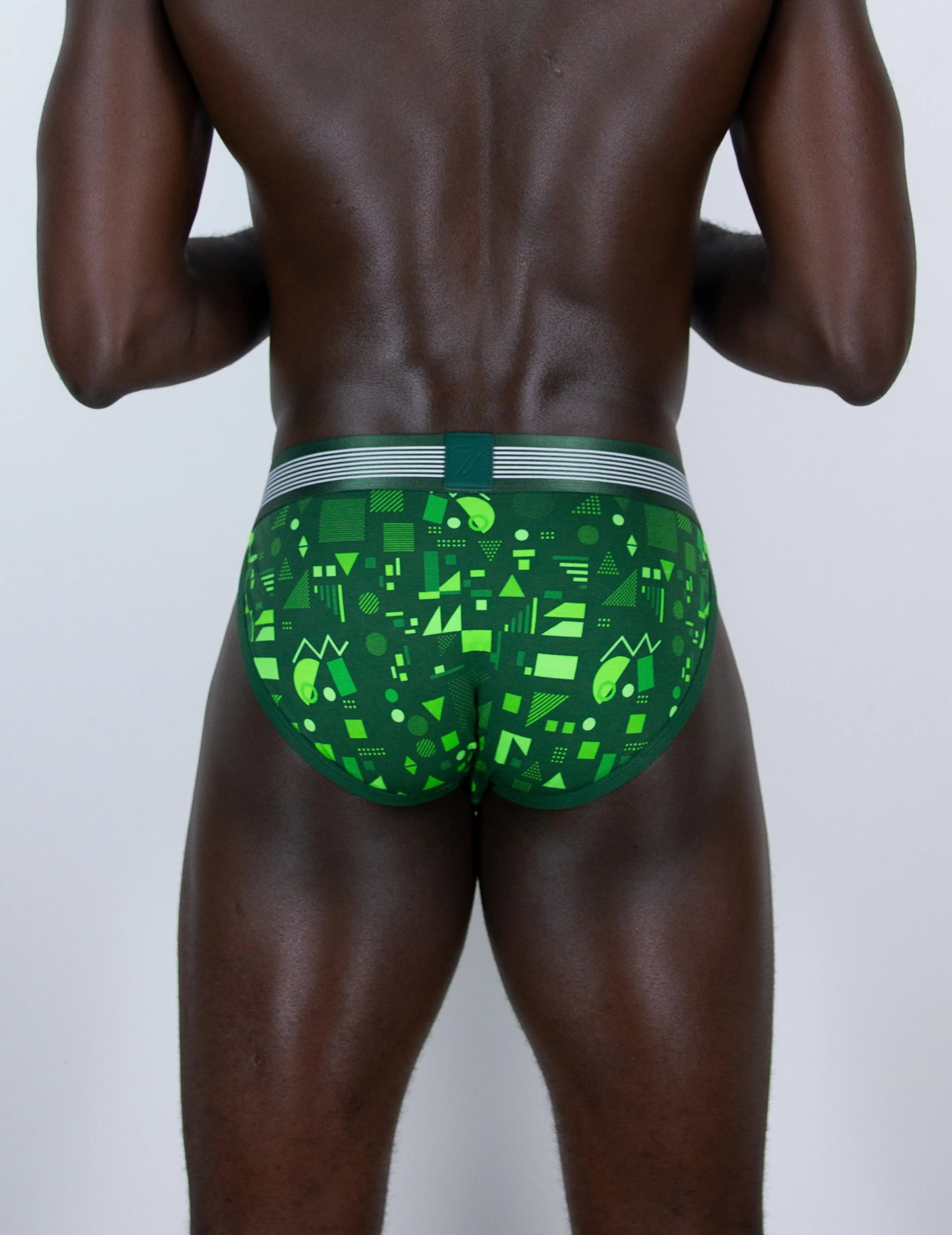 Rear view of a man wearing green patterned sports briefs with a grey and green waistband, shown against a plain light gray background.