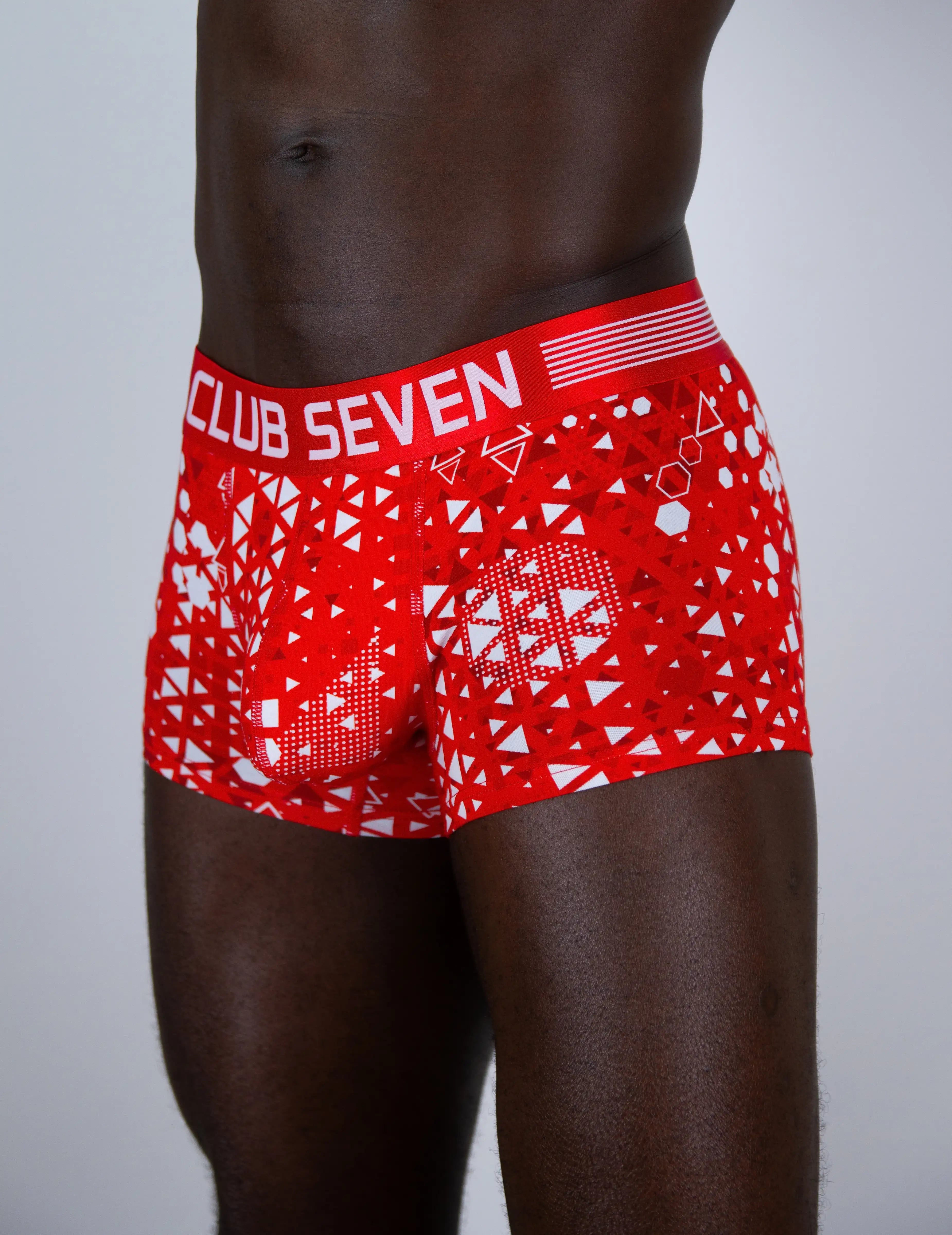 Red and white patterned boxer briefs with 'CLUB SEVEN' printed on the waistband, shown on a male model against a light gray background.